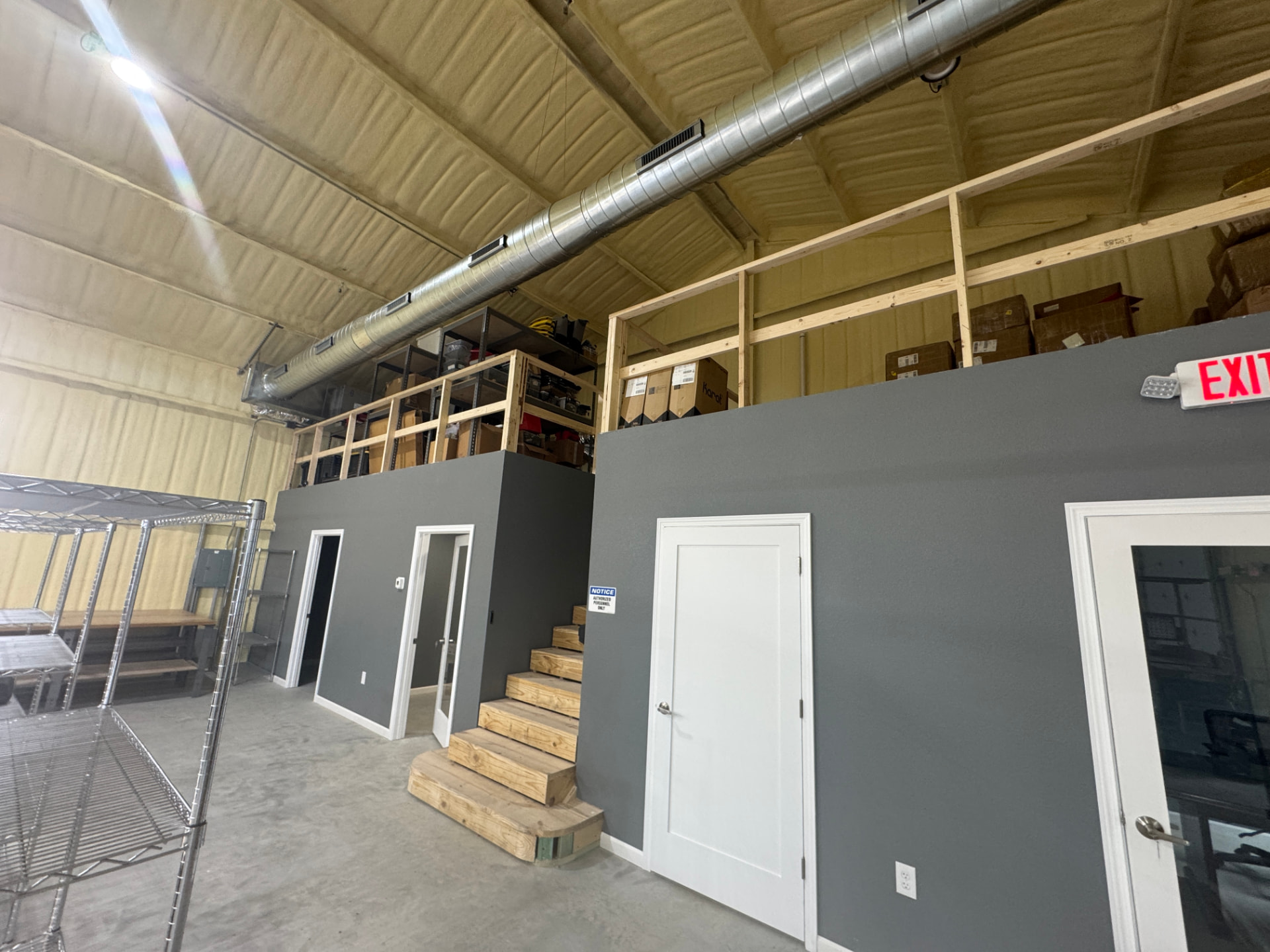 Suite interior with mezzanine storage platform, spray foam insulation, and ductwork